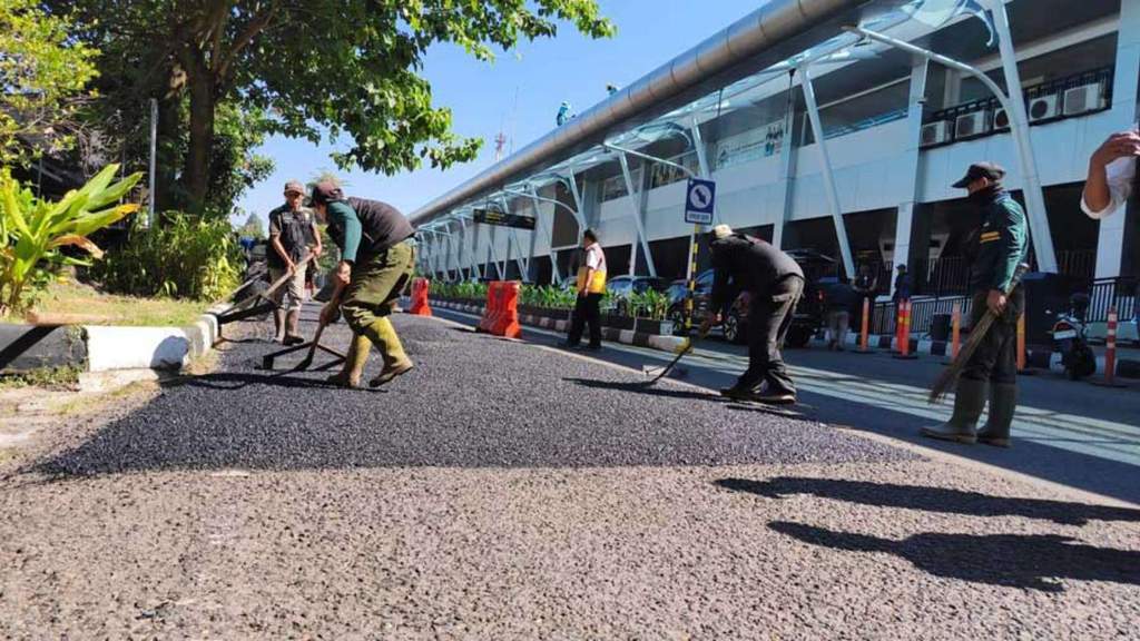 Pekerja Pemkot Bandung melakukan pengaspalan jalan akses menuju Bandara Husein Sastranegara